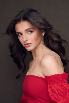 a woman in a red dress posing for a photo with her hair blowing in the wind