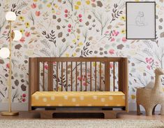 a baby's room with floral wallpaper and a wooden crib in the foreground