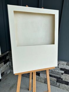 an easel with a painting on it in front of a wall and some bricks