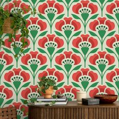 a green and red wallpaper with large flowers on the sideboard next to a potted plant