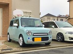 two small cars parked next to each other in front of a building with a satellite antenna on top