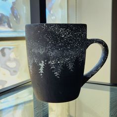 a black cup sitting on top of a glass table