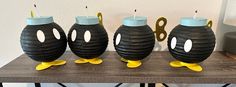 three black and yellow vases with faces on them sitting on a table next to scissors