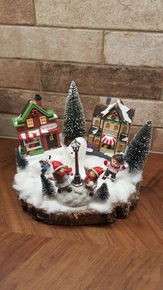 a small christmas village with santas and snowmen in the center on a wooden table