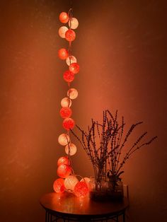 a table topped with a vase filled with flowers next to a string of paper lanterns