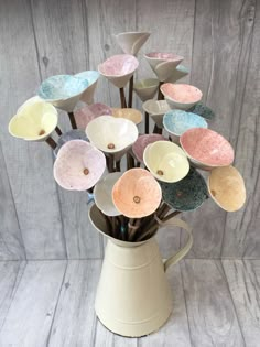 a white vase filled with lots of different colored dishes on top of a wooden table