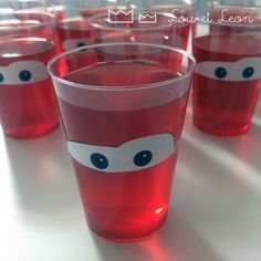 several glasses with red liquid in the shape of a face and eyes are lined up on a table