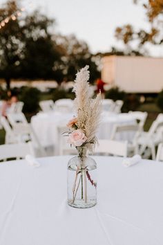 a vase filled with flowers sitting on top of a white table covered in tables cloths