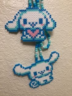 a cross stitch key chain with an elephant on it's side and beads hanging from the end