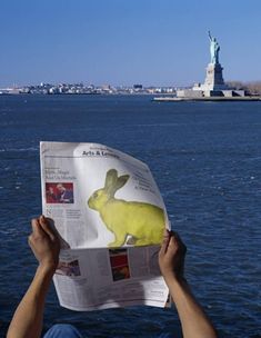 a person reading a newspaper with the statue of liberty in the background