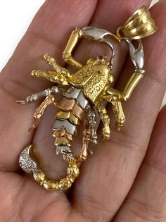 a gold and silver brooch sitting in someone's hand