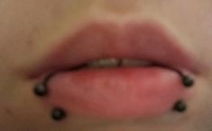 a woman's lips with black beads on them and her tongue sticking out to the side