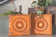 two orange vases with plants in them sitting on a table next to a clock