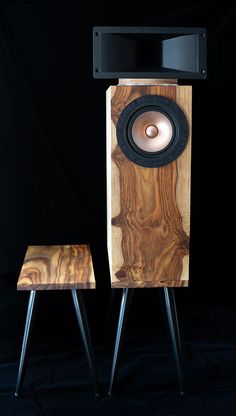 two wooden speakers sitting next to each other on top of metal legs in front of a black background