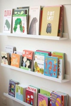 three white shelves with books on them in a children's book store or playroom