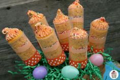 there are some candy sticks in the grass with eggs around them and an orange bow on top