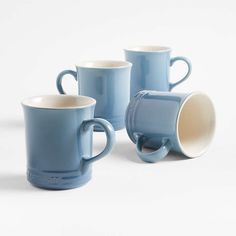 three blue coffee mugs sitting next to each other on a white surface with no one around them