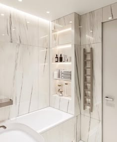 a bathroom with white marble walls and flooring, along with a bathtub in the corner