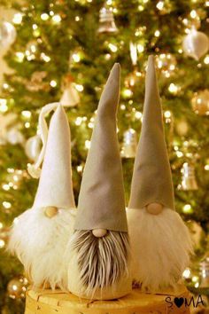 three gnome hats sitting on top of a cake next to a christmas tree with lights in the background