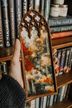 a person holding up a book in front of a bookshelf full of books