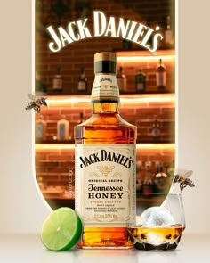 a bottle of jack daniels whiskey next to a glass filled with ice and lime