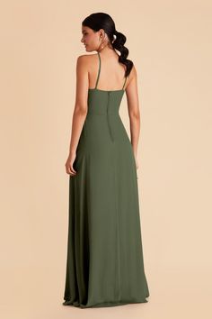 a woman in a long green dress is looking back at the camera and she has her hand on her hip