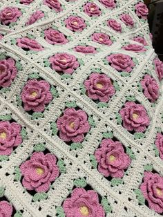 a crocheted blanket with pink flowers on it