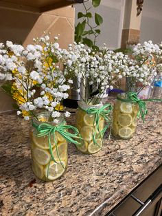 three mason jars filled with lemon slices and baby's breath flowers on a counter