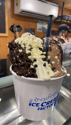 an ice cream sundae is topped with chocolate chips and marshmallows in a paper cup