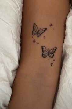 two butterflies flying in the air on a woman's left arm with stars around it