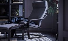 a chair and ottoman in a room with flowers on the table, bookshelf behind it