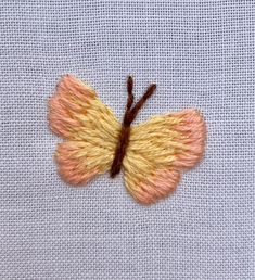 a yellow and brown butterfly sitting on top of a white cloth