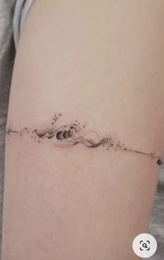 a woman's thigh with a small wave tattoo on it