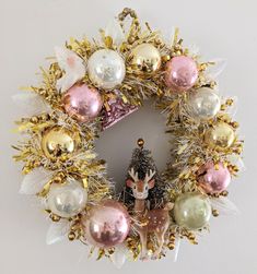 a christmas wreath with ornaments hanging from it's sides and a deer figurine in the middle