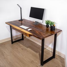 a wooden desk with a computer monitor and keyboard sitting on it's standup