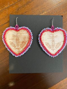 These beautiful earrings are made using birchbark harvested in Wisconsin and finished with beads around the perimeter. The symmetrical pattern on the birch bark is achieved through biting directly onto the bark. The bark is then laminated to protect it. The backing is made out of brain-tanned leather. Bitten birch bark is an ancient native art form. The elder women of the Woodland Nations created this traditional art by biting the birch with their teeth socializing around the campfire. The designs were often used for bead or quillwork.  I am a passionate artist who uses the elements around me to create beautiful pieces of jewelry and art. Everything I make is one-of-a-kind made personally by me in my rural Wisconsin home. Please message with any questions. Thank you for shopping! Birch Bark Earrings, Birch Jewelry, Symmetrical Pattern, Around The Campfire, Birch Bark, Native Art, Campfire, Traditional Art, Beautiful Earrings