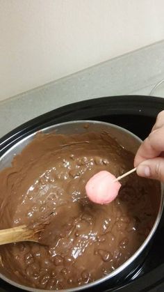 a person stirring chocolate in a pot with a wooden spoon