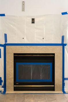 a fireplace with blue tape around it in a room that is being painted white and blue