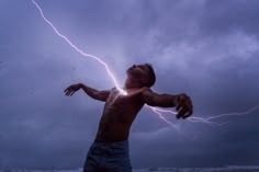 a man standing on top of a beach under a cloudy sky holding a lightning bolt