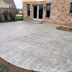 an outdoor patio with concrete pavers in front of a brick building