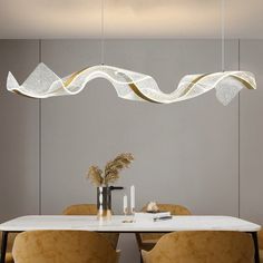 a dining room table with two chairs and a large light fixture hanging over it's head