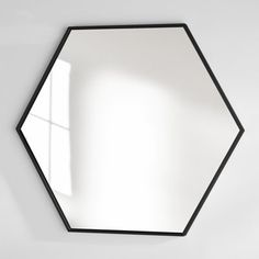 a mirror that is on the wall in front of a white wall with a window