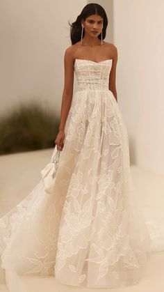 a model walks down the runway in a strapless white gown with floral appliques