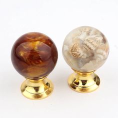 two marble balls sitting on top of gold bases