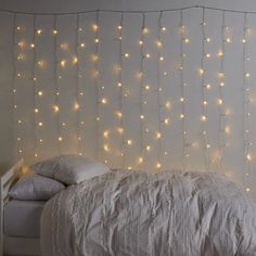 a bed with white sheets and lights hanging from the headboard