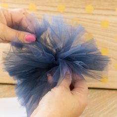 a person holding a piece of tulle on top of a wooden table