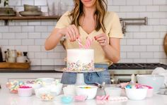 a woman standing in front of a cake with pink and white frosting on it