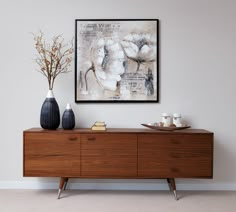 two vases sit on top of a wooden dresser in front of a framed painting