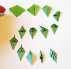 someone is making origami airplanes out of green paper and pointing to them with their fingers