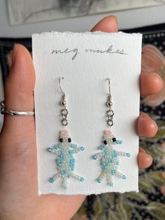 a pair of blue and white beaded earrings in front of a card that says, hey make's